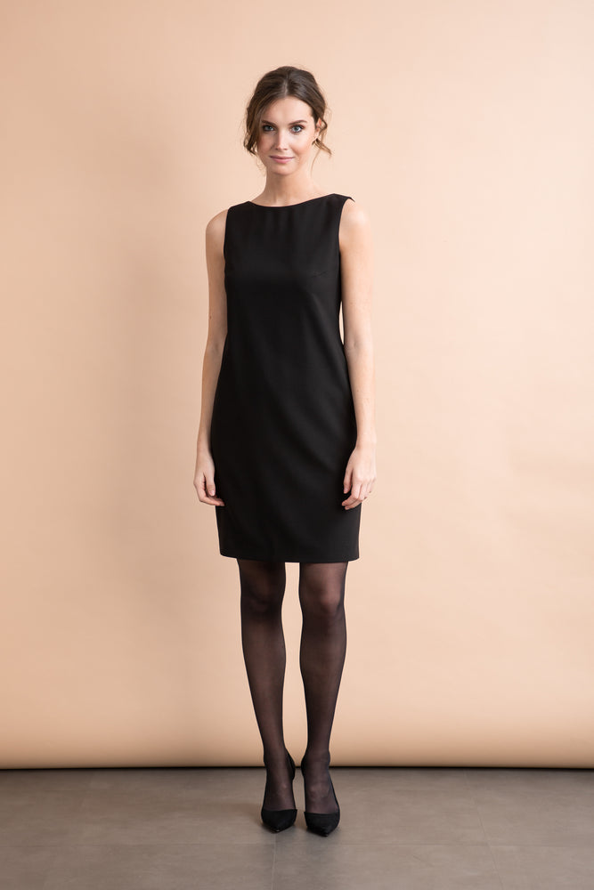
                  
                    a woman in a black dress standing next to a wall 
                  
                