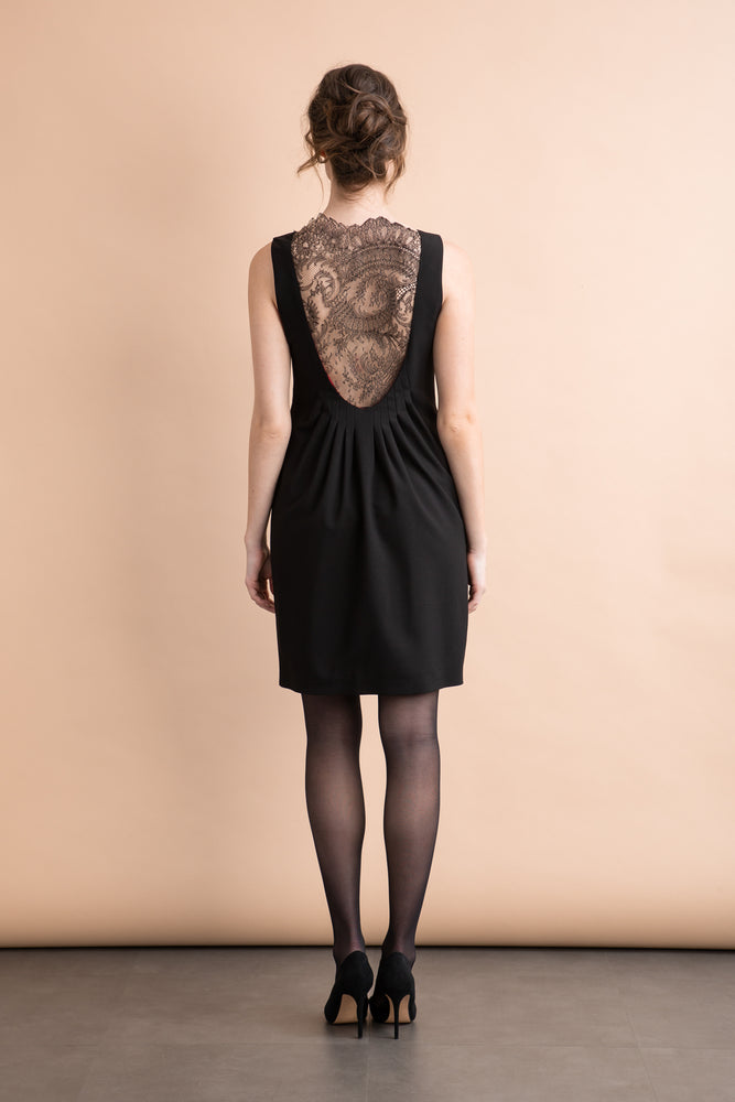 a woman in a black dress standing in front of a wall 